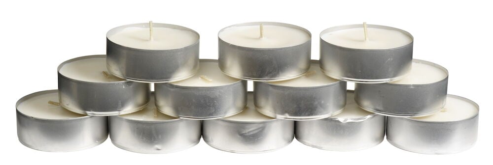 Zwölf weiße Teelichter gestapelt in Aluminiumformen.