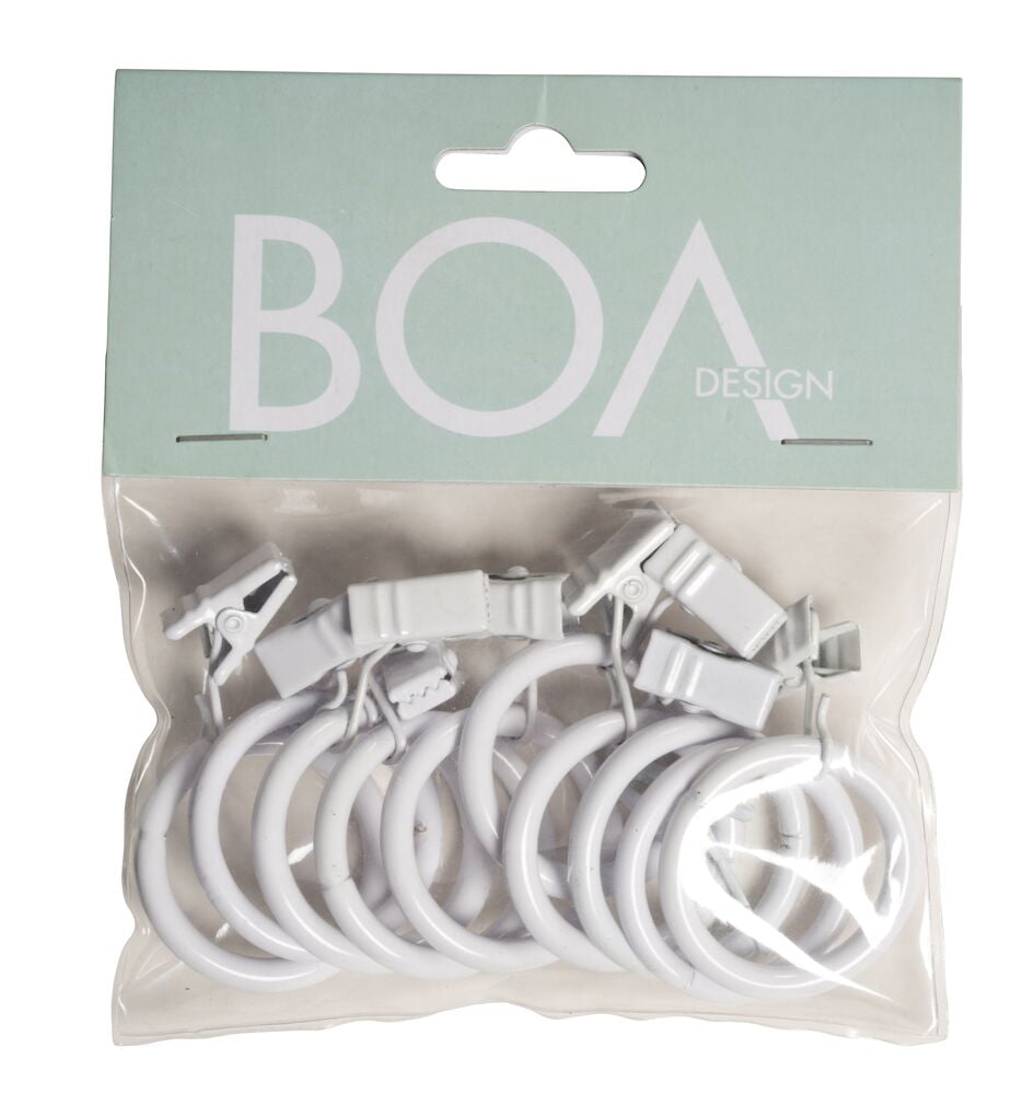 Kymmenen valkoista verhorengasta, joissa on klipsi, muovipakkauksessa.