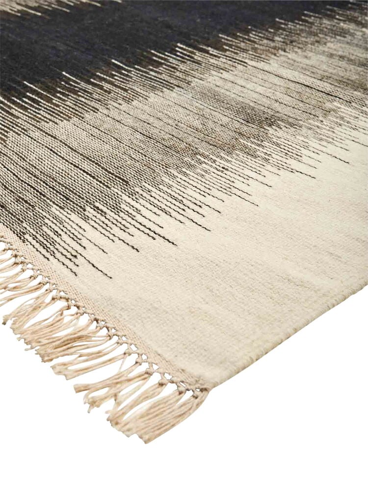 Käsinkudottu mustavalkoinen kelimmatto, jossa on hapsut.