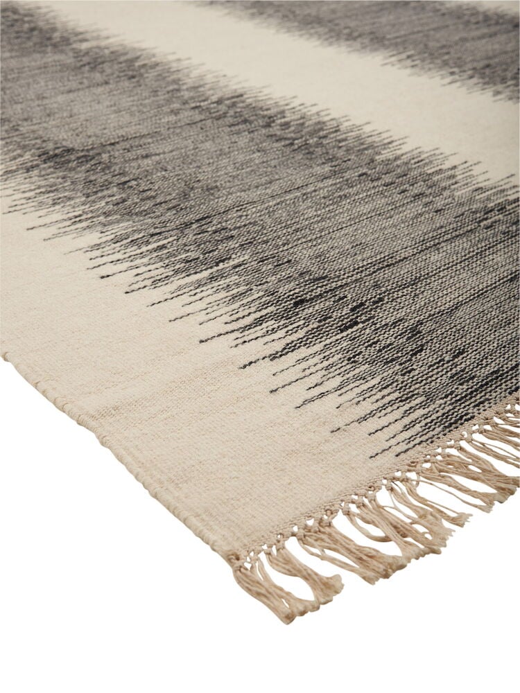 Mustavalkoinen villamatto, jossa on hapsut ja kuvioitu pinta.