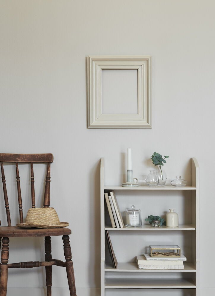 Ljusgrå målad hylla bredvid trästol och vägg.