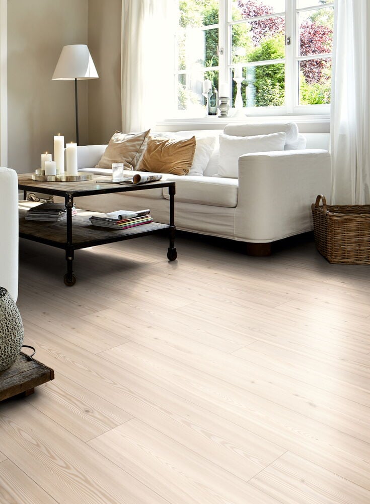 Ljust laminatgolv i vardagsrum med vita möbler.