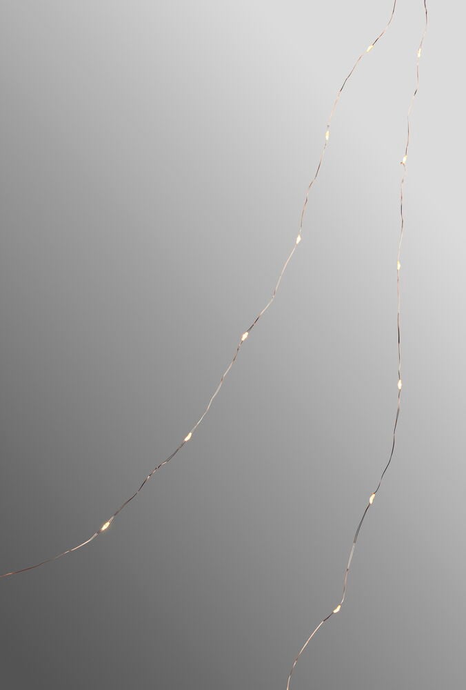 Kuparin värinen Valoketju Sirlig, jossa 50 lämpimän valkoista LED-valoa, harmaalla taustalla.