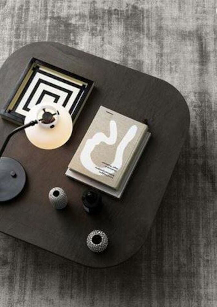 Handvävd grå matta under mörkt soffbord med dekoration.