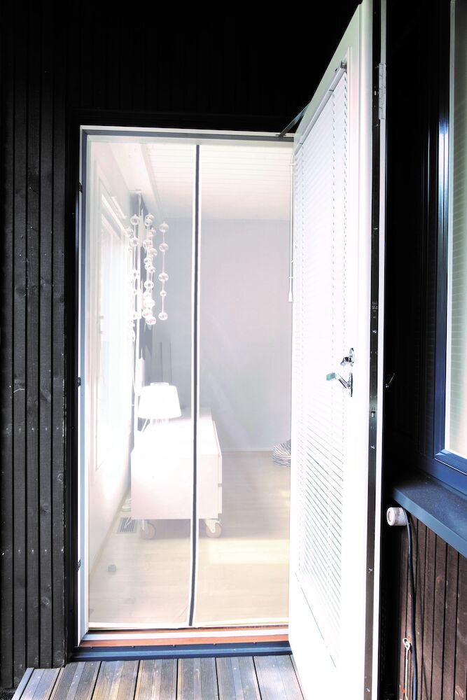 Valkoinen oviverho kahdessa osassa parvekkeen oveen.