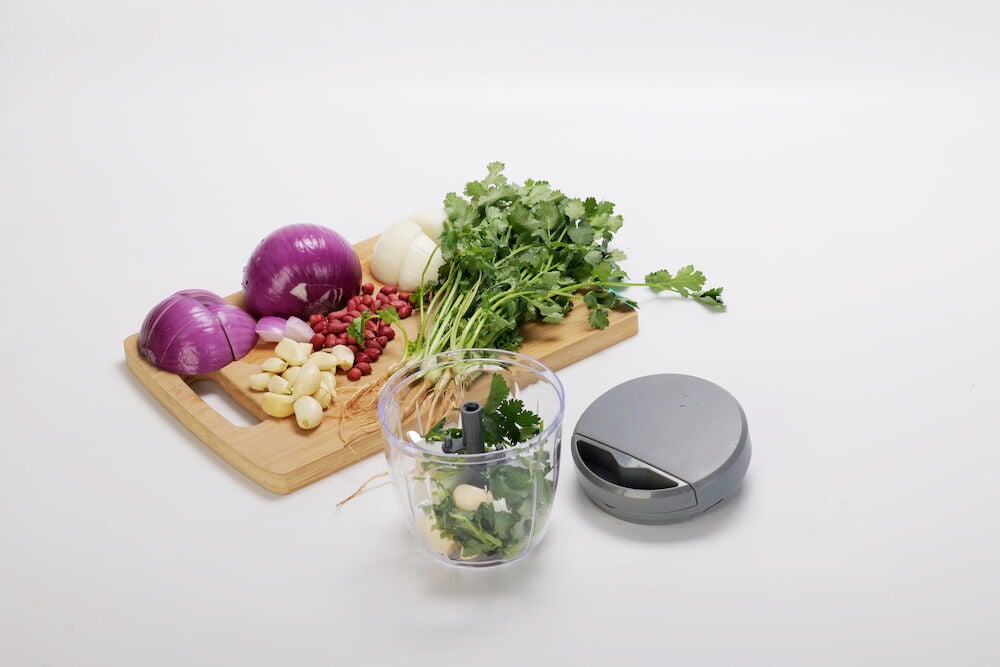 Hacker in Plastik neben Schneidebrett mit Gemüse.