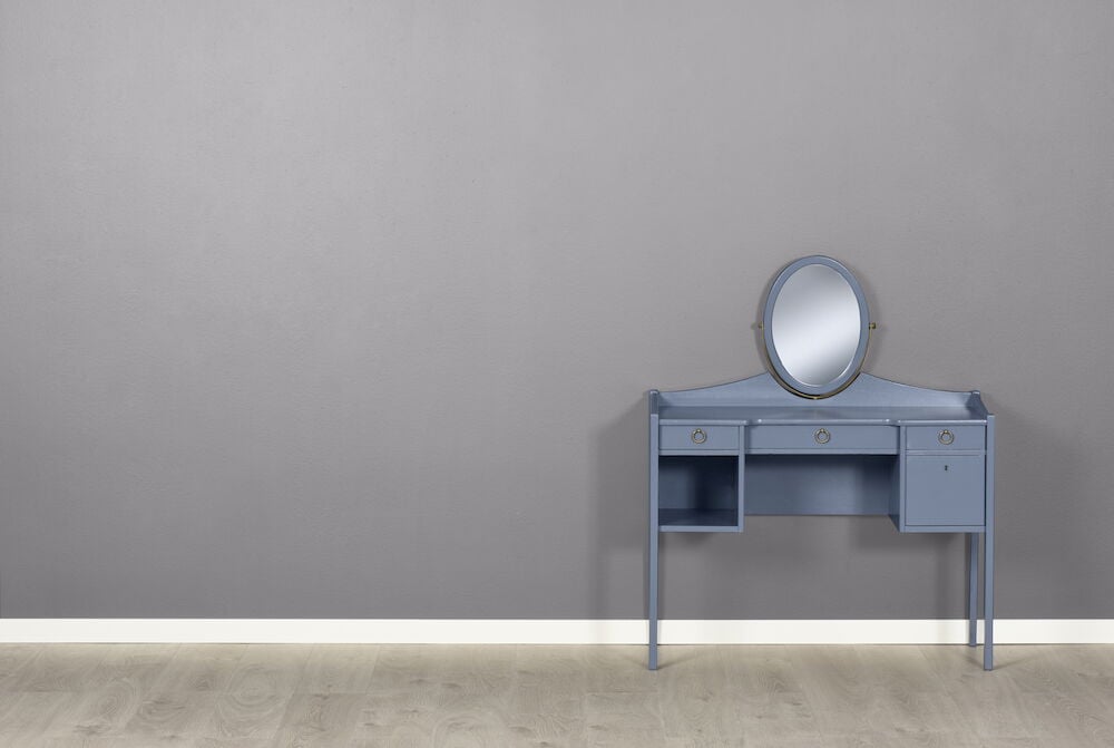 Grå silk matt vägg med blå sminkbord och spegel.