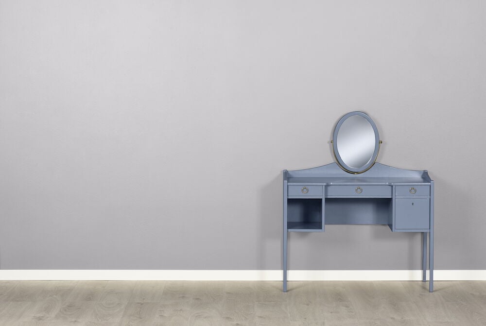 Ljusgrå vägg med blått sminkbord och spegel.