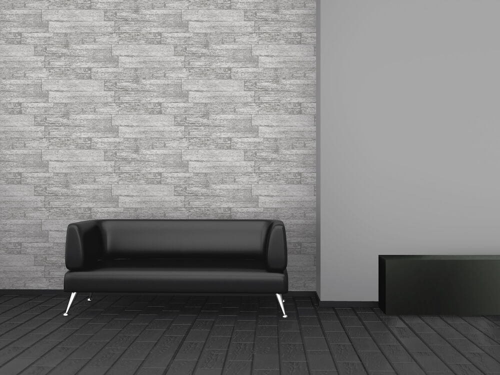 Grå tapet med drivvedstruktur bakom svart soffa.