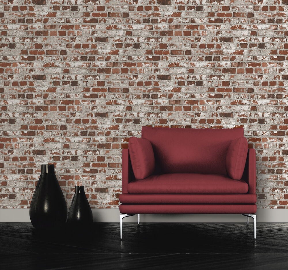 Röd fåtölj framför rustik brun tegeltapet.