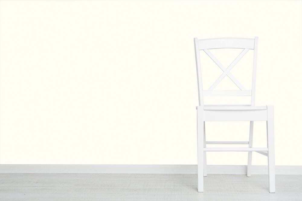 Vit tapet med diskret struktur bakom vit stol.