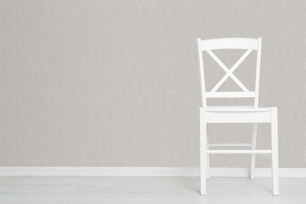 Vit stol framför ljusgrå slät tapetvägg.