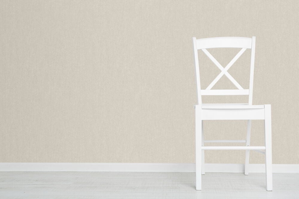 Beige enfärgad tapet och vit trästol mot vägg.