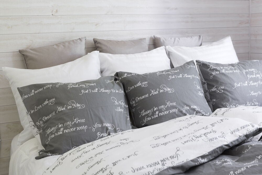 Harmaa puuvillainen pussilakanasetti tekstikuviolla.