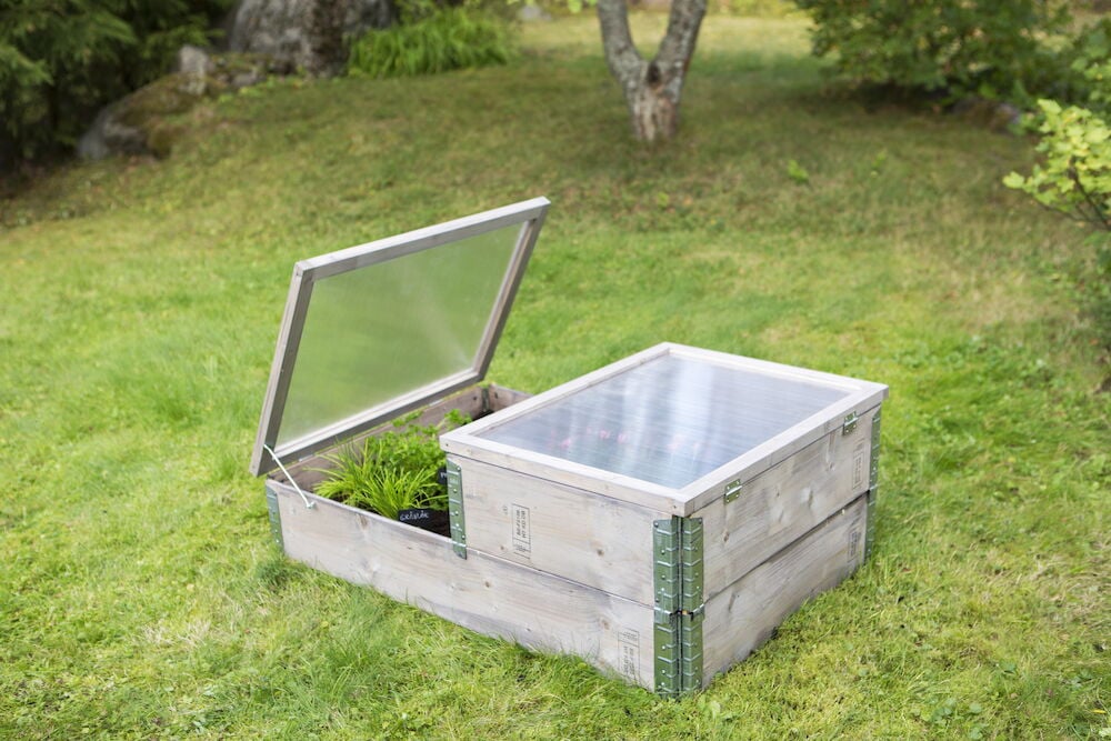 Pallkrage i naturträ med öppet lock på gräsmatta.