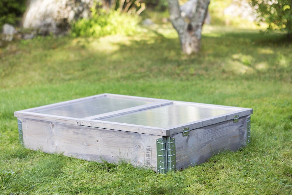 Träpallkrage med lock placerad på gräsmatta.