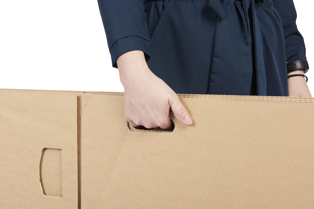 Hand bär brun flyttkartong med handtag.
