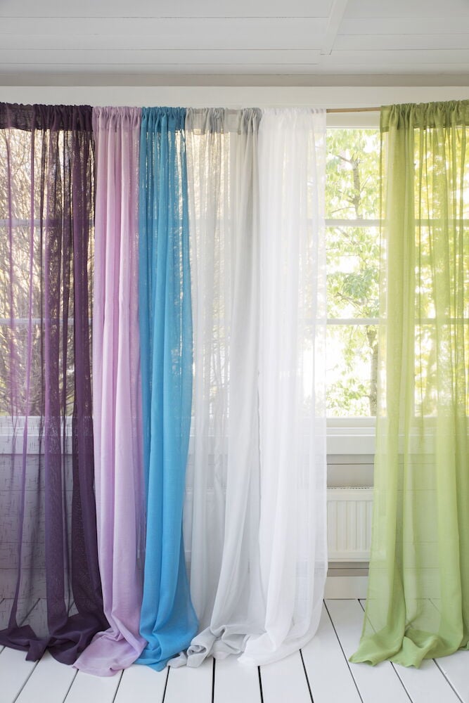 Useita verhotankoja eri väreissä ikkunan luona.