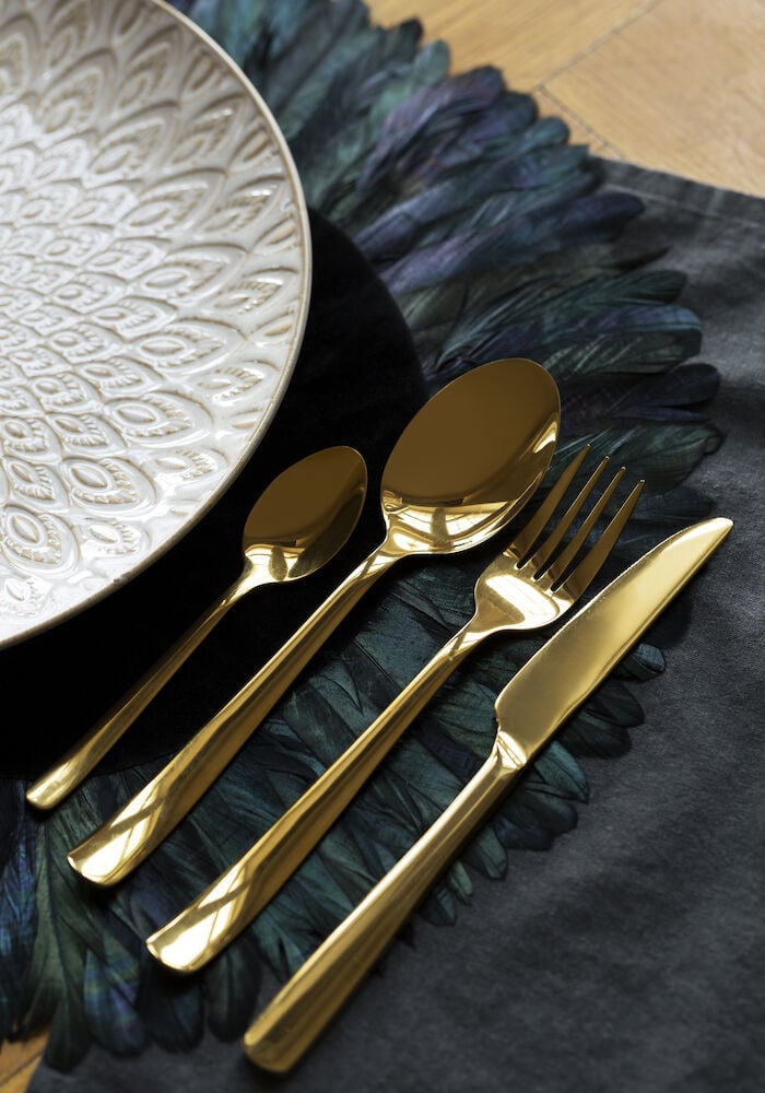 Neljä kultaväristä aterinta lautasen vieressä.