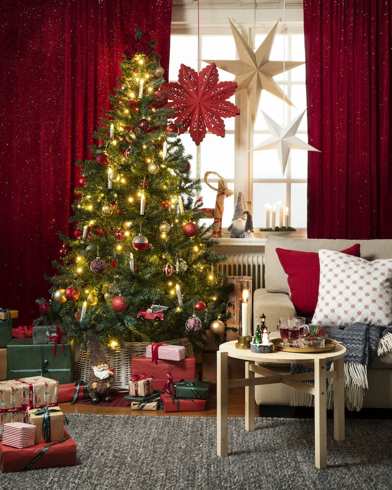 Harmaa käsinkudottu matto sohvapöydän alla joulukuusen vieressä.