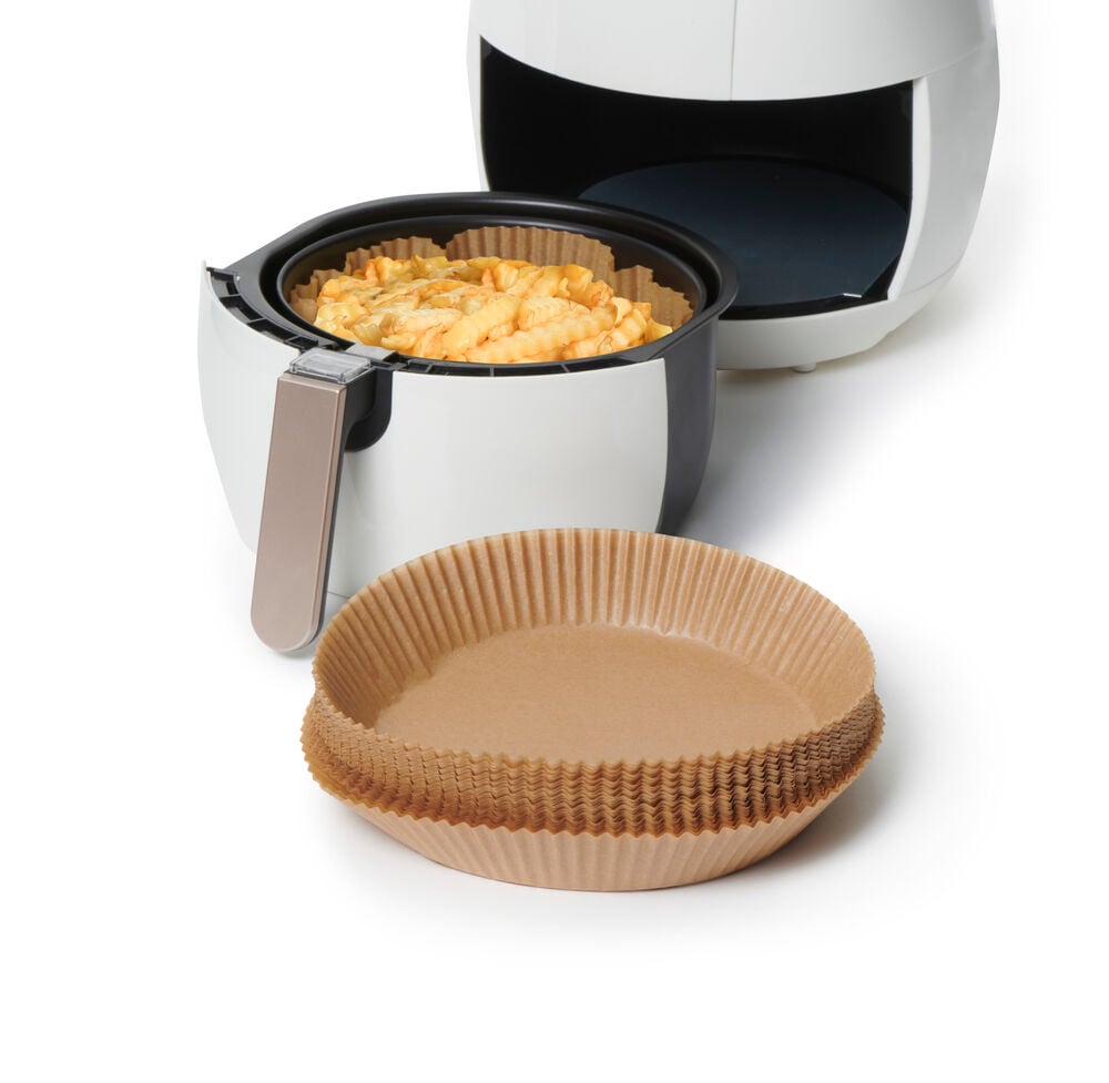 Runda bruna airfryer papper framför en airfryer.