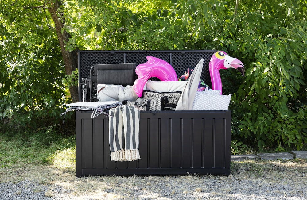 Svart förvaringslåda utomhus fylld med olika saker.