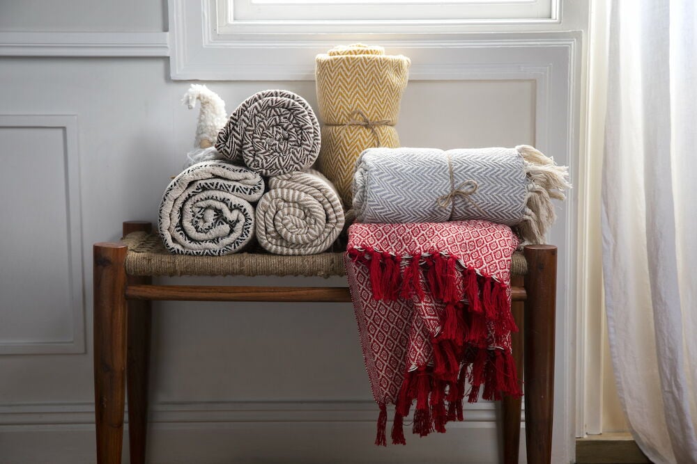 Mehrere gerollte Baumwolldecken auf Holzbänken.