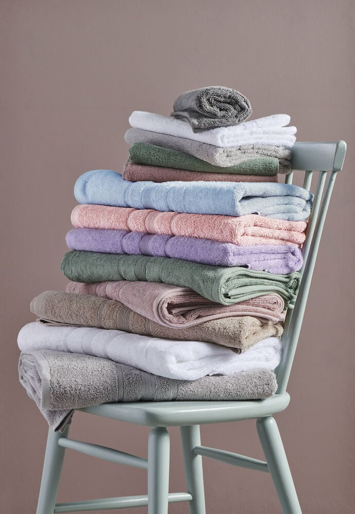 En stapel färgglada handdukar på en stol.