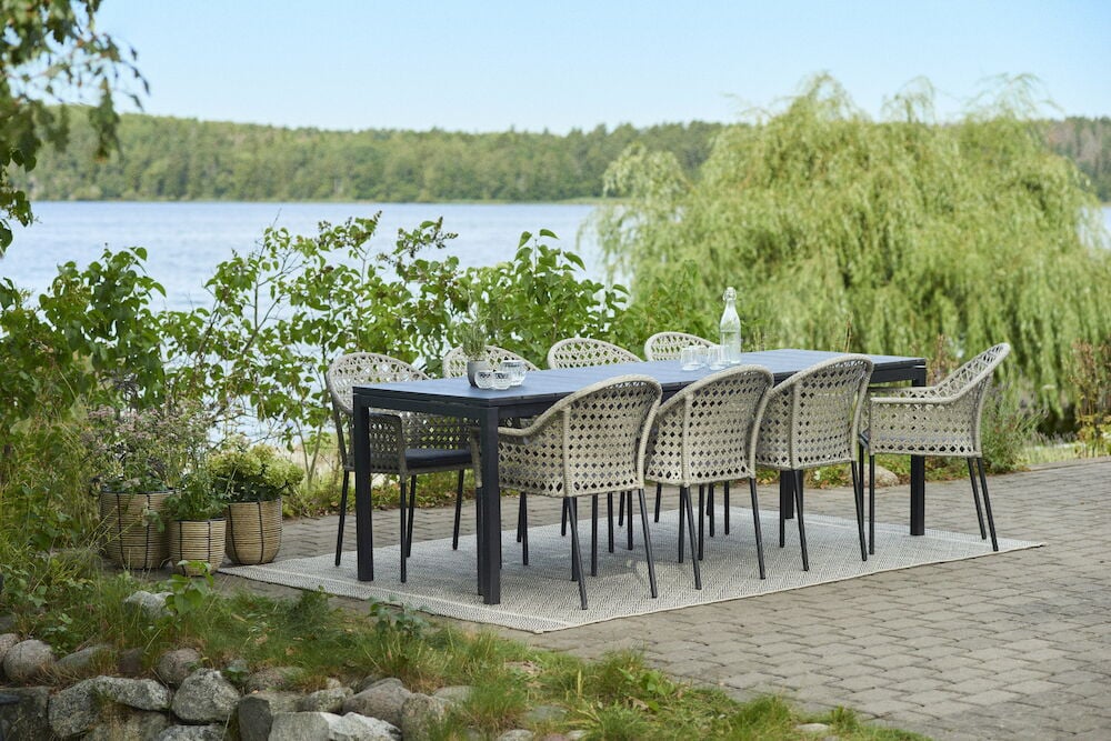Ruokaryhmä, johon kuuluu kahdeksan punottua tuolia ulkona järven rannalla.