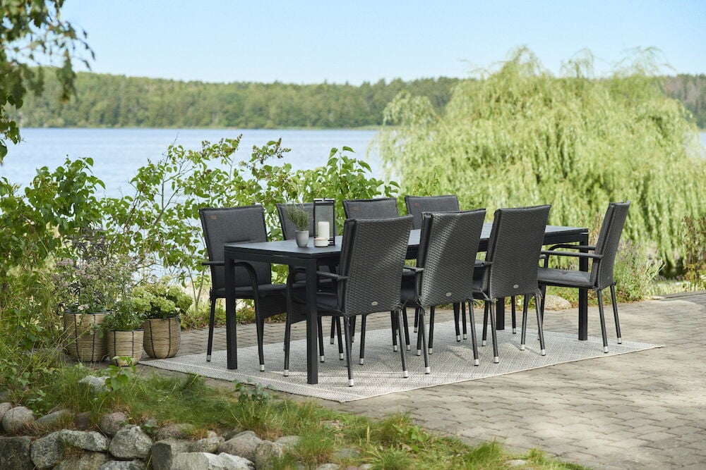 Svarta dynor på matstolar vid uteplats med bord.