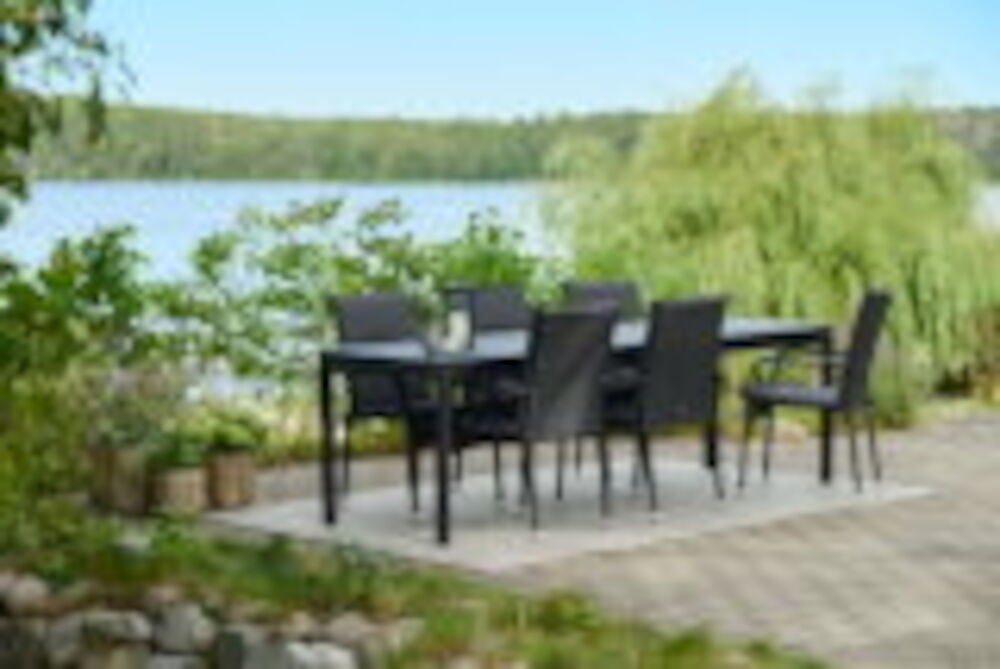 Svart rektangulär dyna på stol vid utebord.