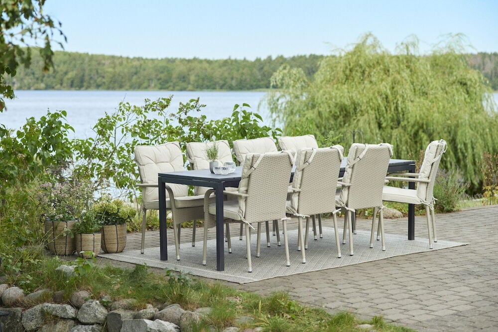 Vaaleat tyynyt ulkotuoleilla mustan ruokapöydän ympärillä.