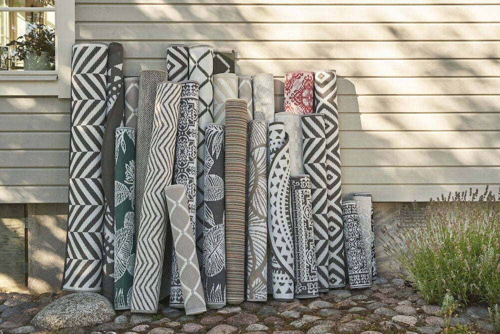 Flera hoprullade utomhusmattor i olika mönster och färger.