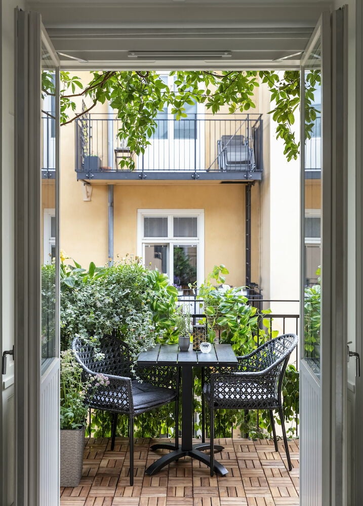 Nelikulmainen musta kahvilapöytä, jossa kaksi tuolia ulkona.