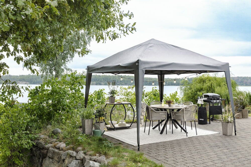 Rundt svart bord med fire stoler under paviljong.