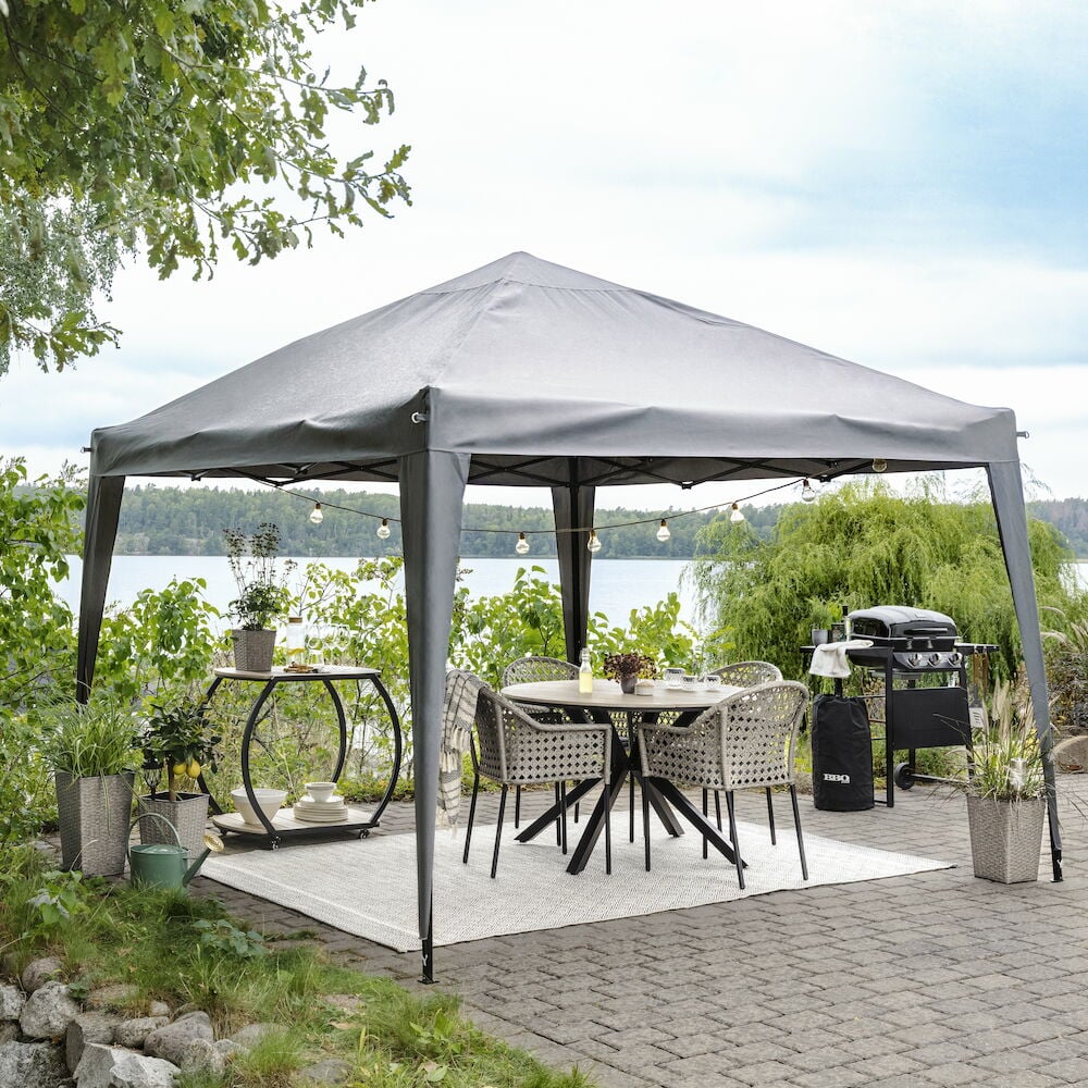 Rundt svart bord med fire stoler under paviljong.