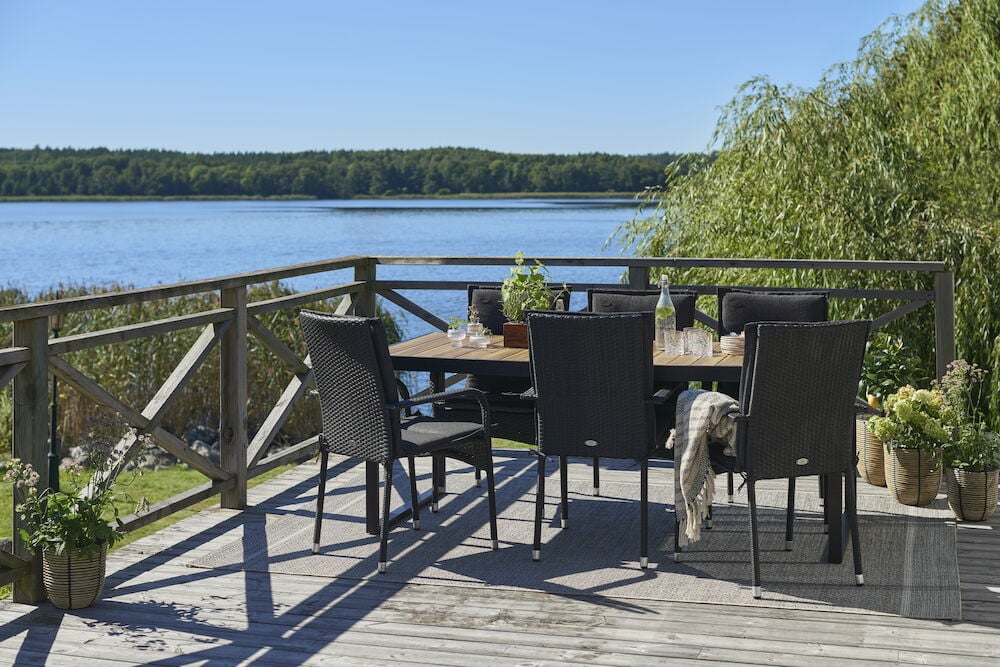 Musta istuintyyny tuolilla ulkopöydän ääressä, josta on järvinäköala.