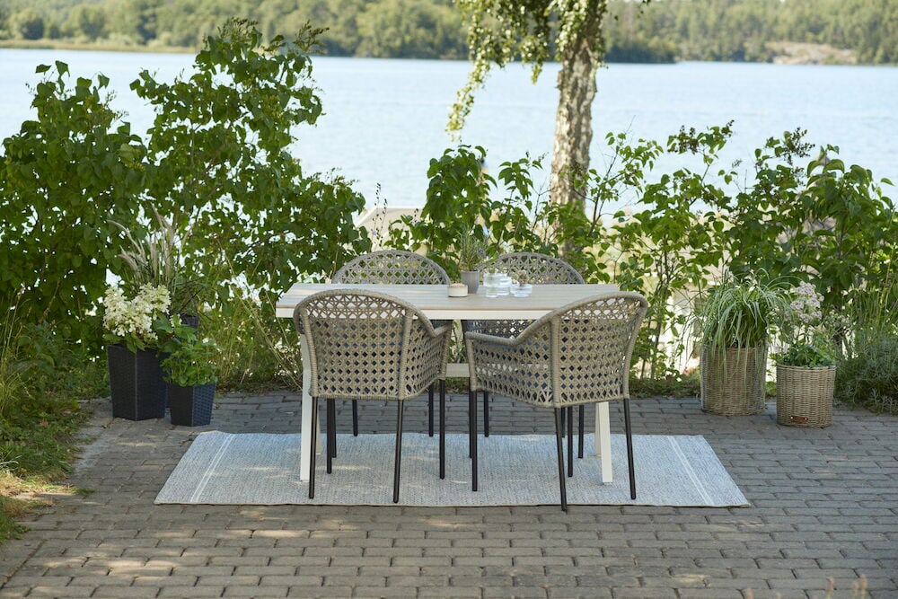 Valkoinen ulkopöytä, jossa on neljä tuolia terassilla.