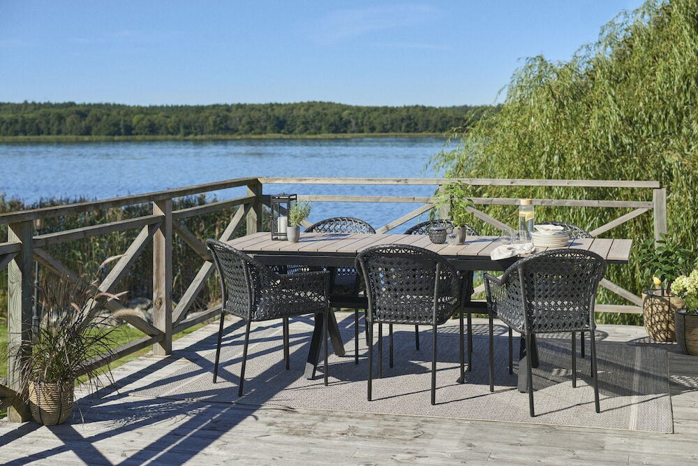 Sisäänvedettävä musta pöytä, jossa kuusi mustaa tuolia.