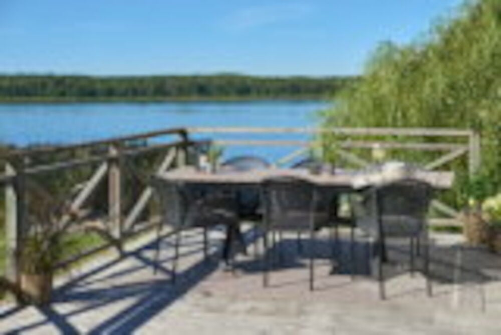 Musta jatkettava pöytä terassilla järven rannalla.