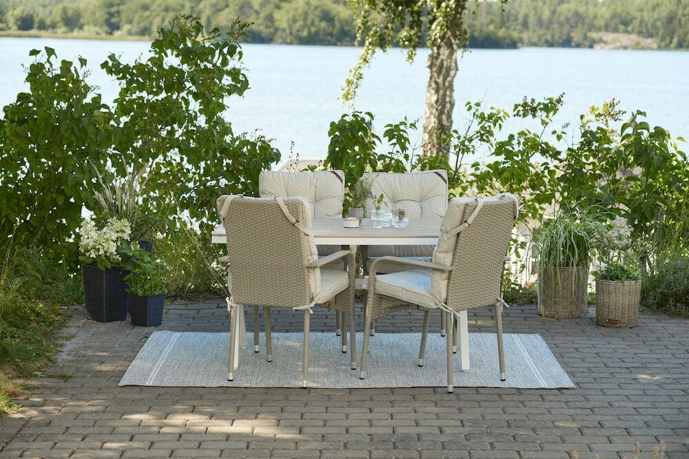 Valkoinen suorakulmainen pöytä, jossa neljä tuolia ulkona.