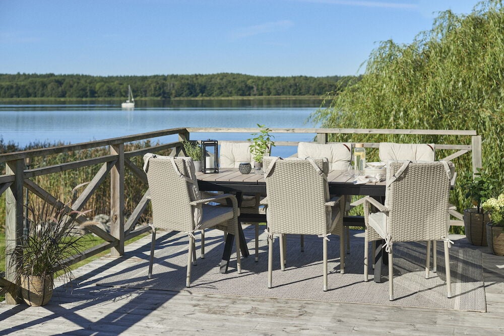 Musta ulosvedettävä pöytä ja vaaleat tuolit terassilla.