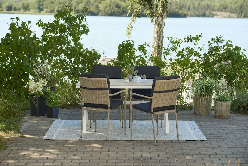 Vitt rektangulärt bord med fyra stolar utomhus.