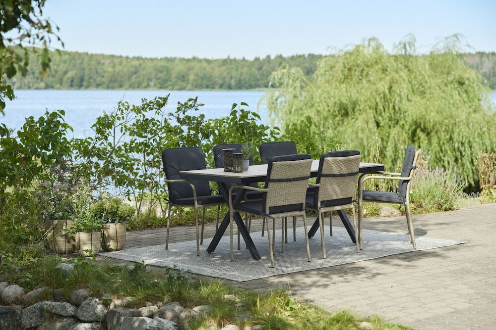 Vitt utdragbart matbord med sex svarta stolar utomhus.