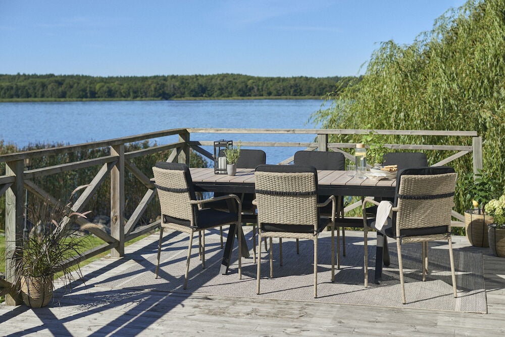 Utemöbler med ryggstödssittdynor på altan vid sjö.