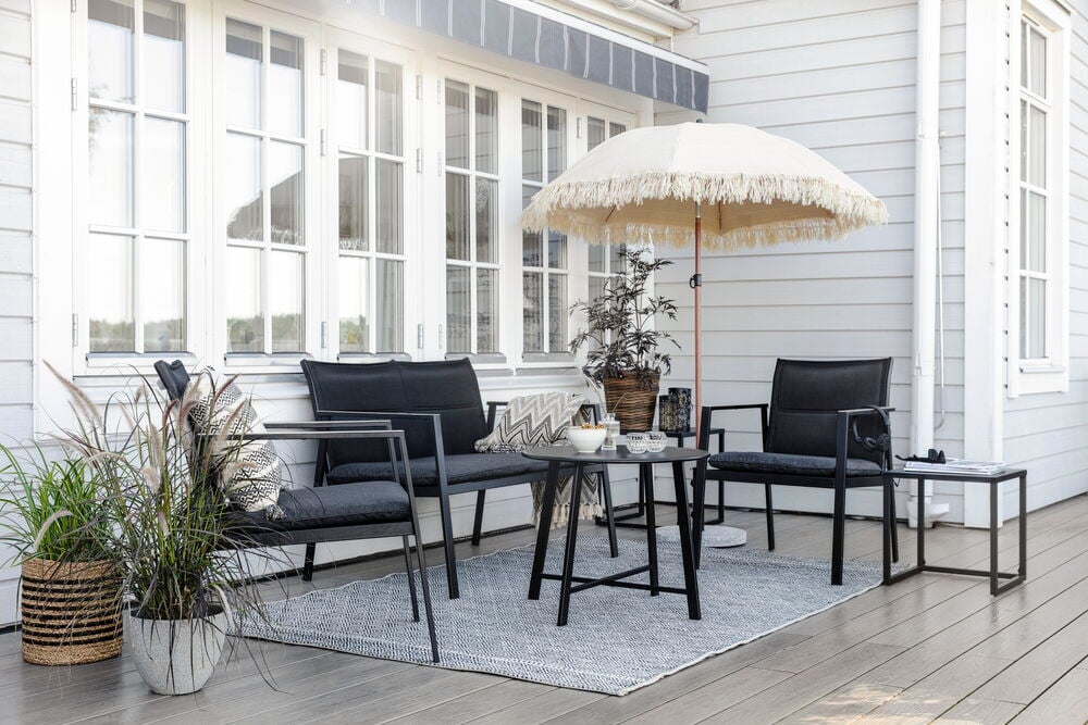 Vaalea aurinkovarjo hapsuilla terassilla ulkokalusteiden kanssa.