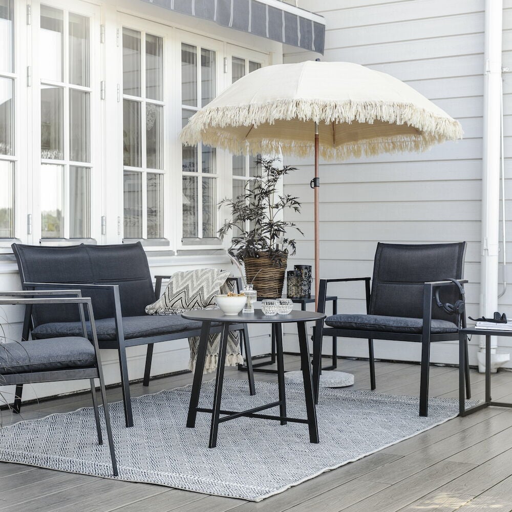 Musta oleskeluryhmä, jossa on kaksi nojatuolia, sohva ja pöytä.