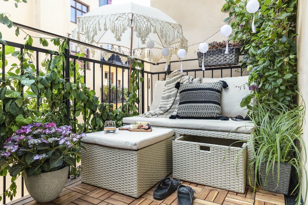 Vit parasoll med dekorativa tofsar och flätade detaljer.