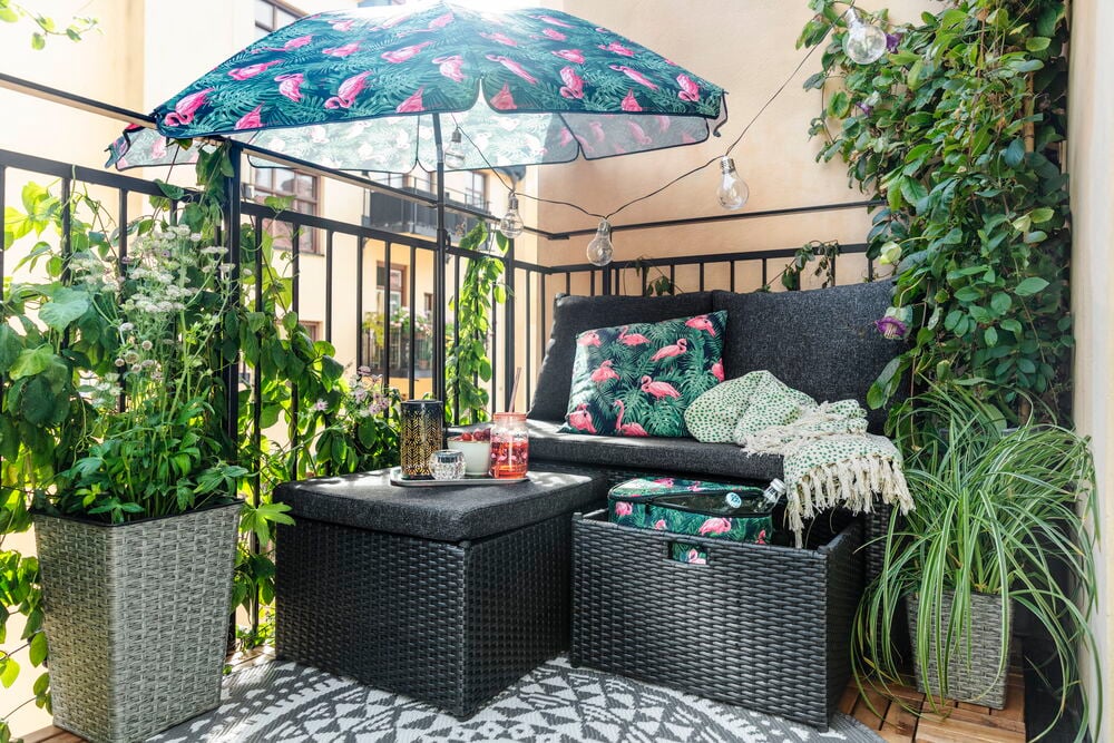 Svart loungesofa i kunstrotting med puter og ramme