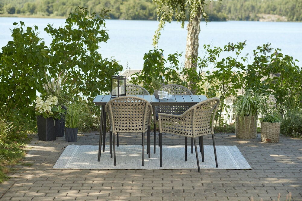 Mustat istuintyynyt ulkotuoleilla pöydän ääressä lähellä järveä.